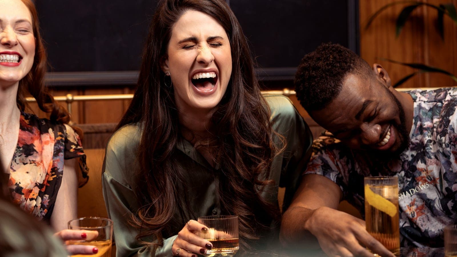 Group of friends laughing over drinks at a bar